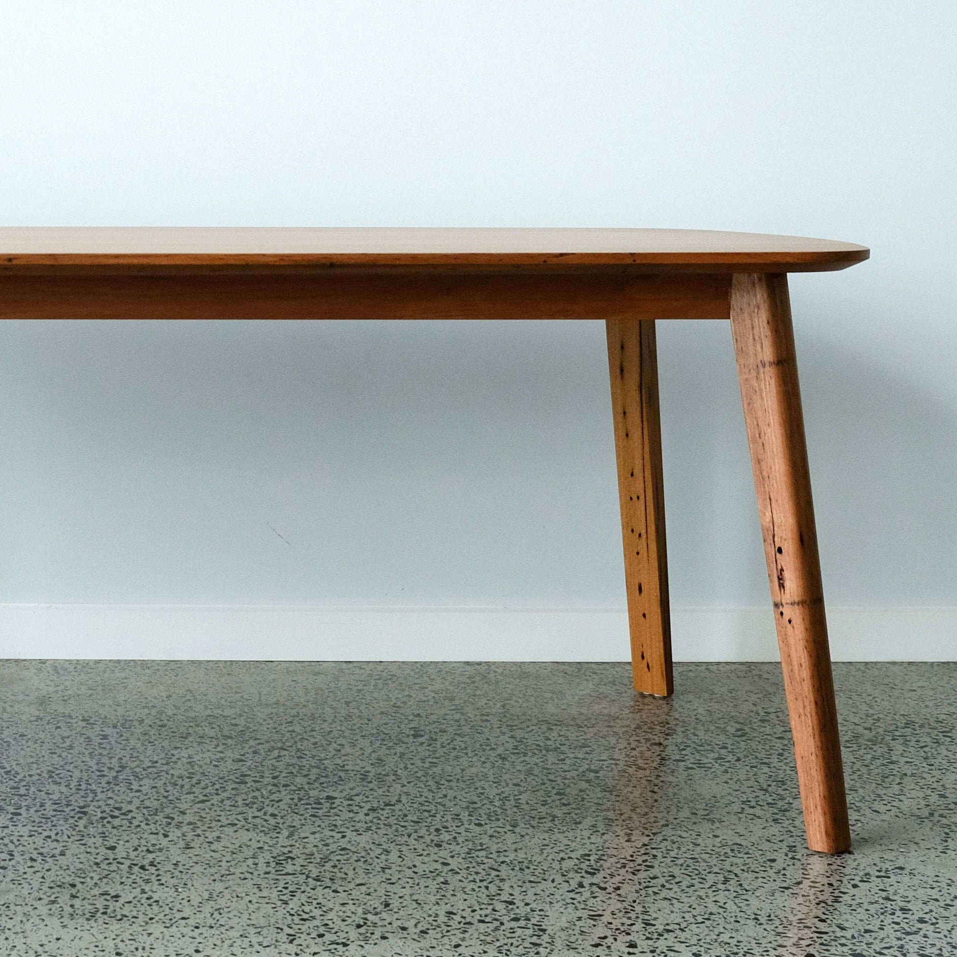 reclaimed timber dining table on a concrete floor and light gray wall background