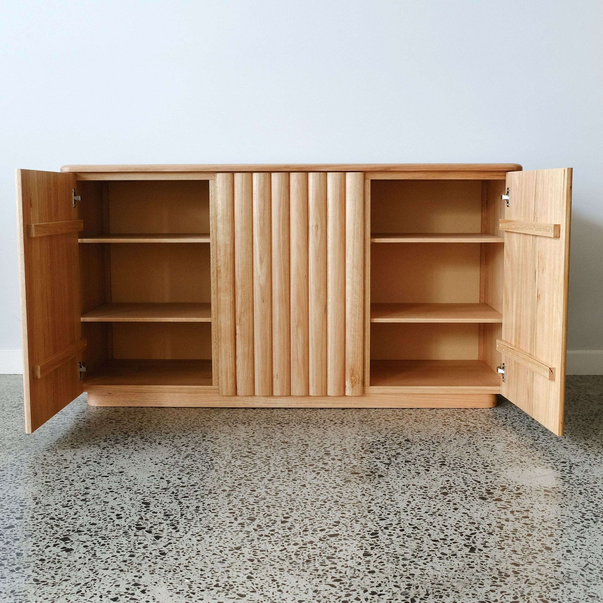 Wooden cabinet with open doors on a speckled gray floor.