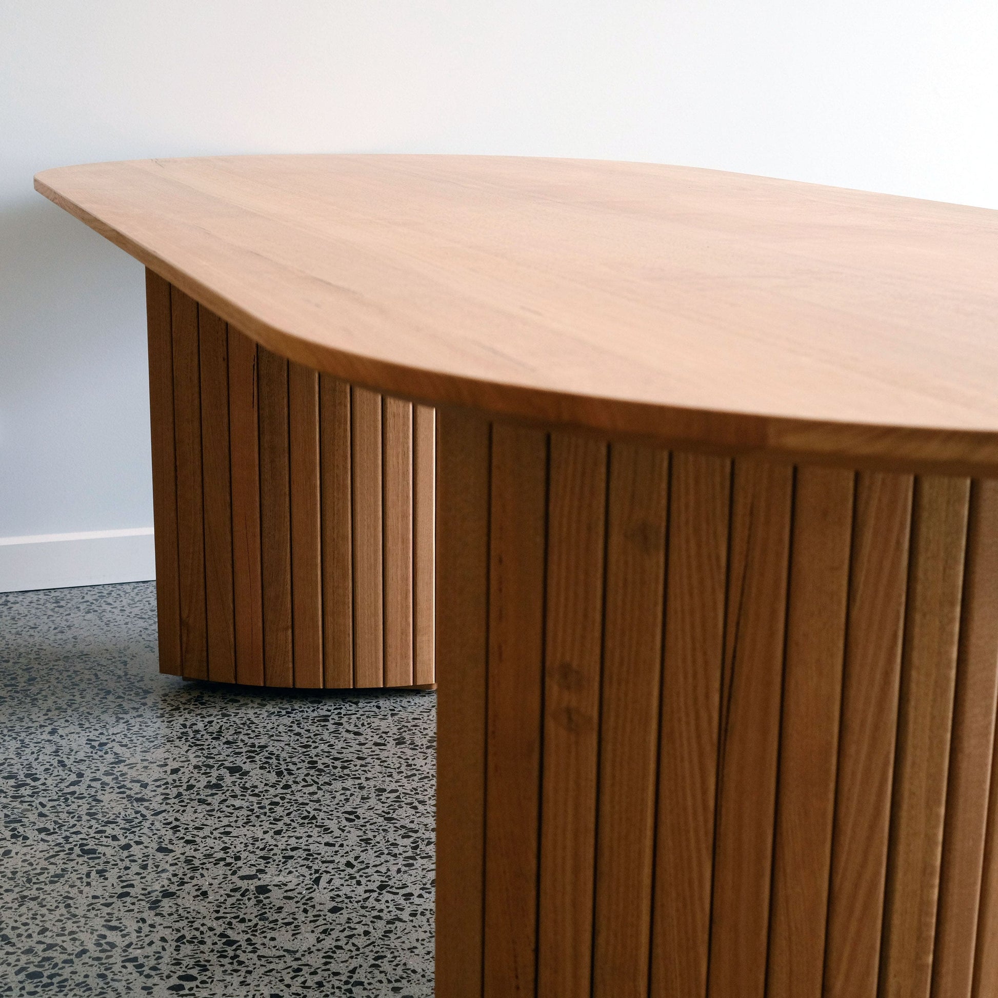 Bespoke dining room table with a curved top on a gray floor.