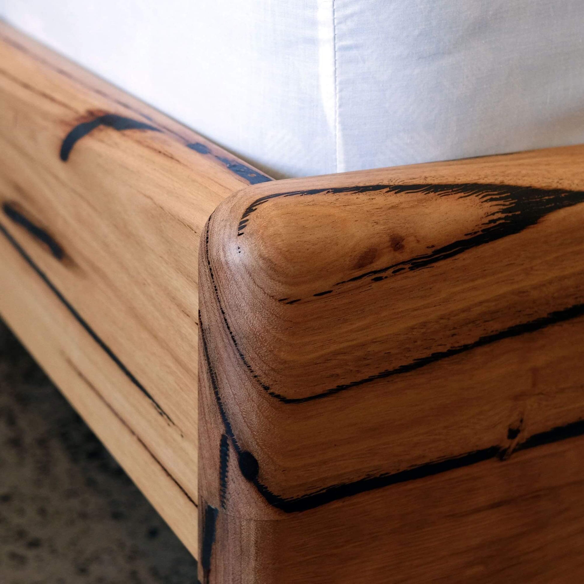 Close-up of the Plymouth Panel Timber Bed in Recycled Messmate showcasing sleek curved edges and natural wood grain.