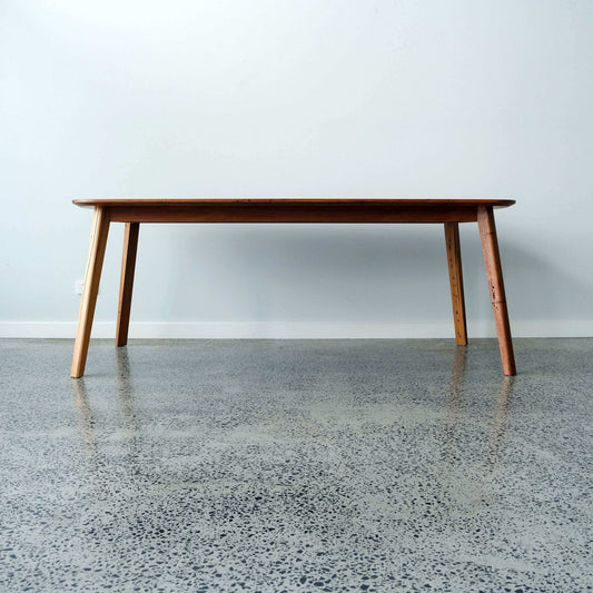 reclaimed timber dining table on a concrete floor with a light gray wall background