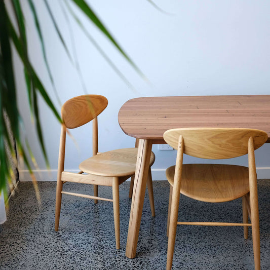 reclaimed wood dining table and chairs in a room with a plant.