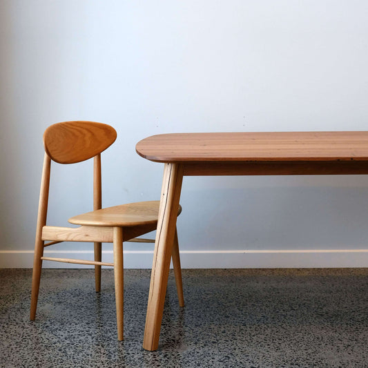 reclaimed timber dining table and oak dining chair against a plain wall.