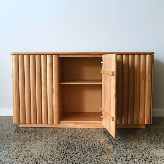 Wood cabinet with open door on a concrete floor against a light blue wall