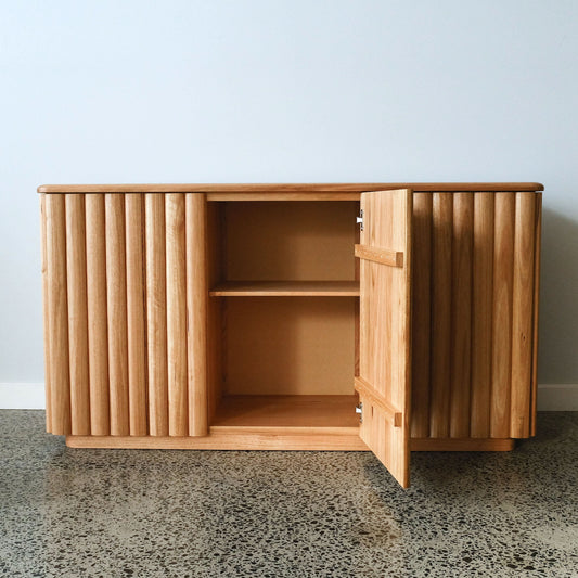 Tassie oak cabinet with open door on a concrete floor against a light blue wall