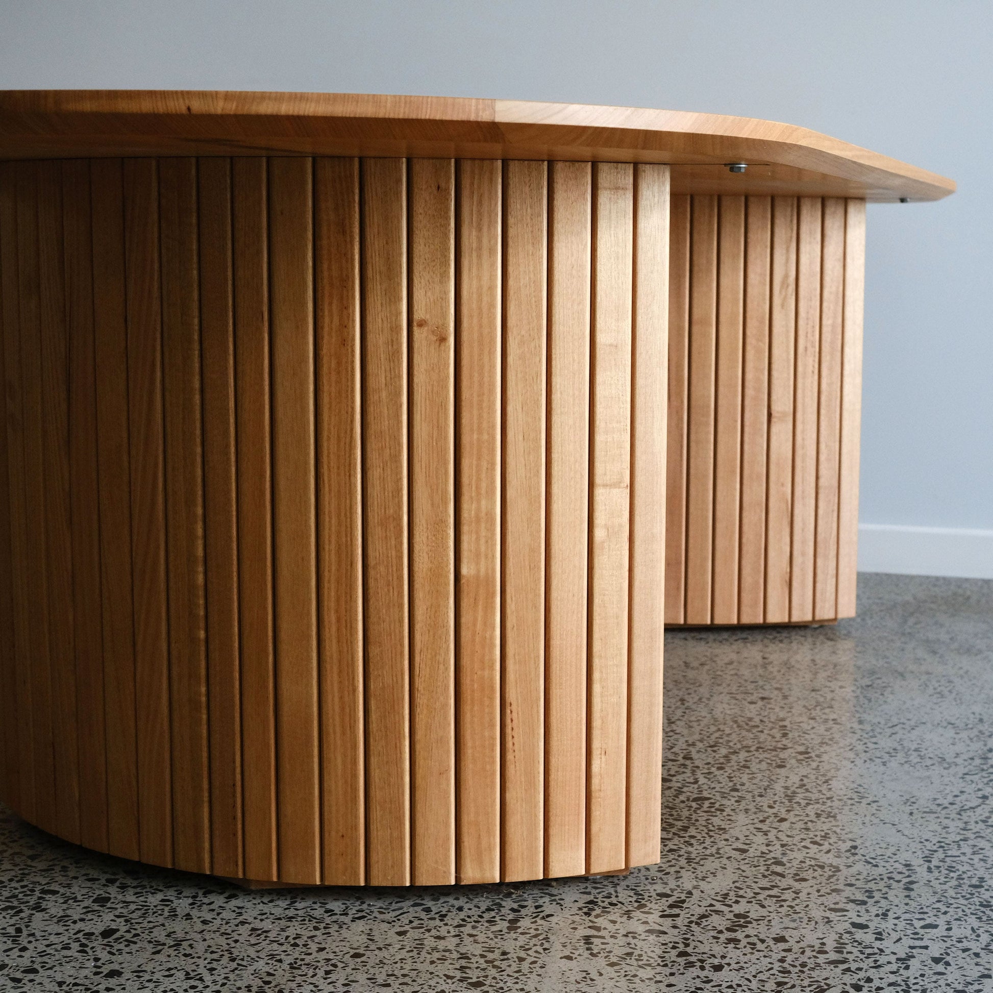 oak timber dining table with a modern design on a gray floor.