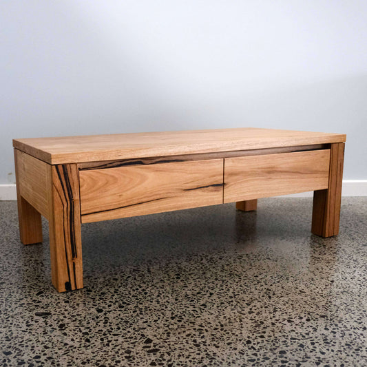 Messmate coffee table with two drawers on a concrete floor.
